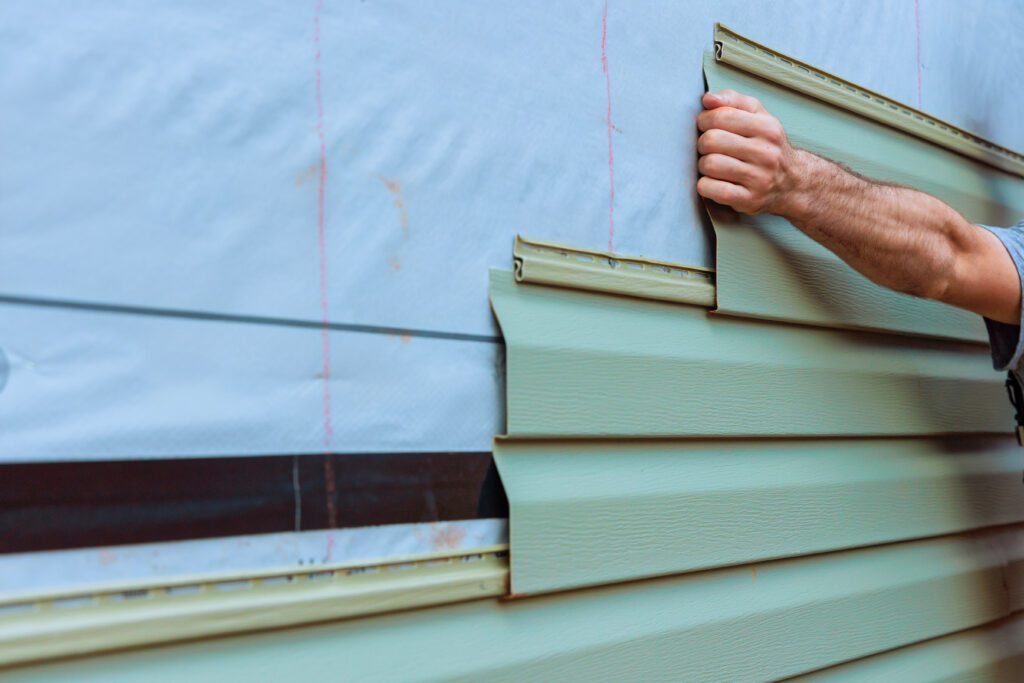 a man installing vinly siding to a home